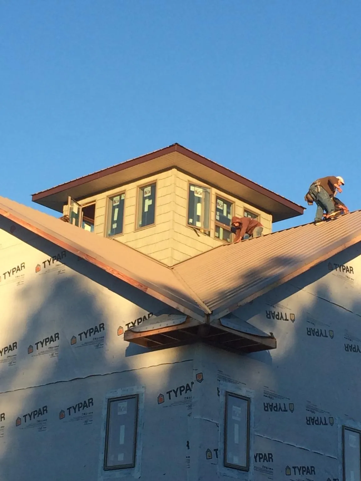 Roofers working around a rooftop cupola on a new metal roof at sunset — Roof Waterproofing in Monroe by Roofing Brothers